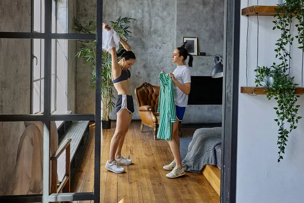 La mujer se está cambiando de ropa en el apartamento del loft y su hermana la está ayudando.. —  Fotos de Stock