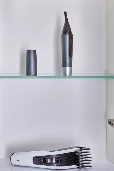 Huishoudelijke apparaten voor thuis kapsels zoals neus, wenkbrauw en oorschaar en hoofd tondeuse worden opgeslagen in badkamer wandkast. — Stockfoto