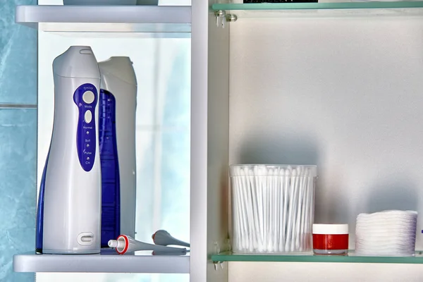 El riego oral se almacena en el gabinete de pared del baño junto con otros artículos de higiene. — Foto de Stock