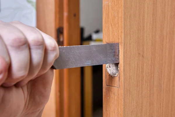 Usando cincel, el carpintero corta el agujero para la tira del pestillo de la puerta. — Foto de Stock