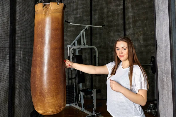 Bolso de boxeo en el gimnasio, mujer joven entrena golpes. —  Fotos de Stock