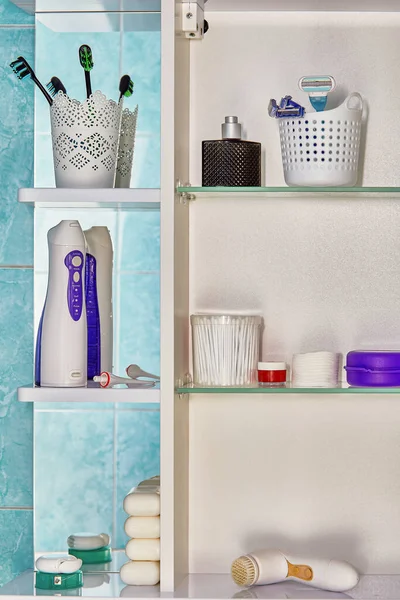 Persoonlijke hygiëne items, waaronder een orale irrigator, bevinden zich op planken van de muur kast in de badkamer. — Stockfoto