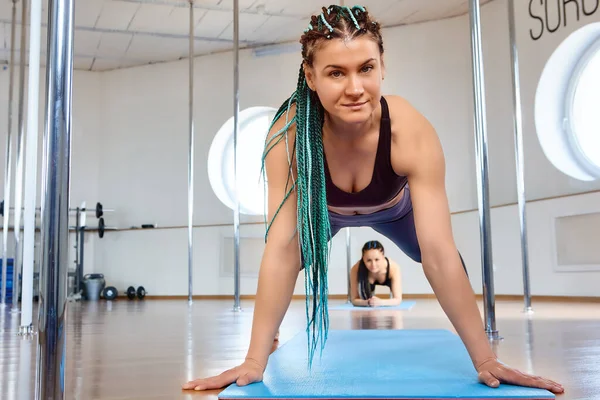 Klasser i gym av pole dance studio, idrottare gör övningar för styrka och flexibilitet. — Stockfoto