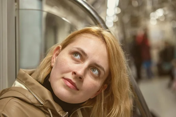 Young white woman rides subway car and looks to side and up. — Zdjęcie stockowe