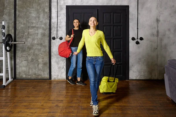 Arriving from vacation, women enter apartment with travel bags and smiles on their faces. — Stok fotoğraf