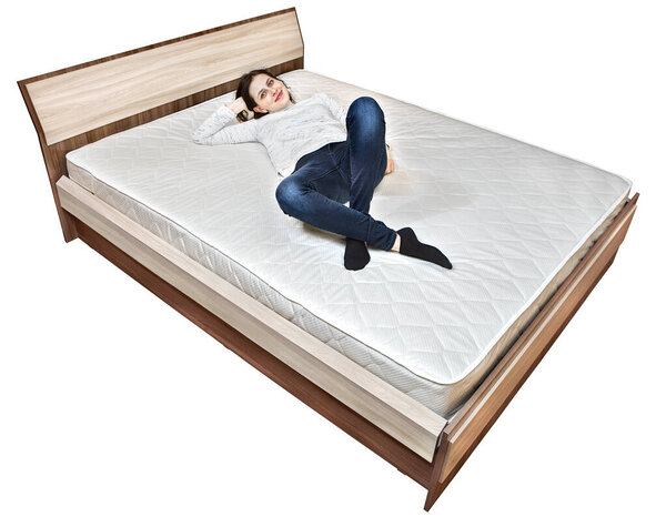 Bed frame with headboard and double mattress on which young European woman lies.