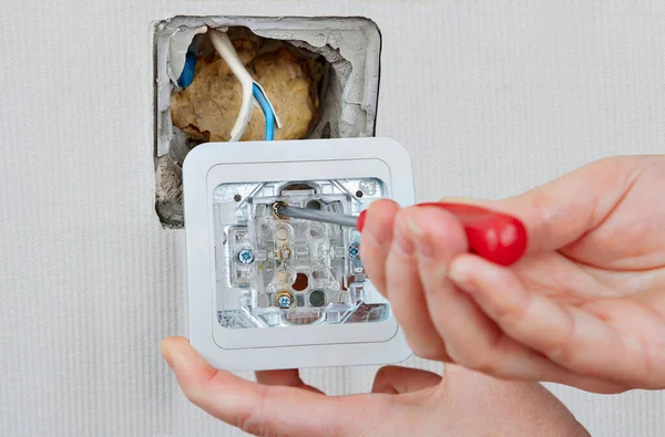 Substituindo ou reparando interruptor de luz interior, eletricista instala aparelho e conecta fios elétricos para caixa. — Fotografia de Stock