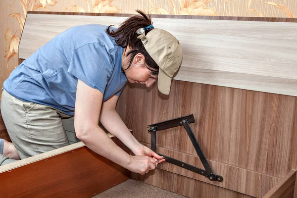 Installing spring loaded lift mechanism on bed with storage compartment when assembling furniture from flat pack. — Stock Photo, Image