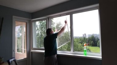 Konut alanına sivrisinek ağlı pencere ekranı kurulumu. Olgun adam odaya sineklik koyar.