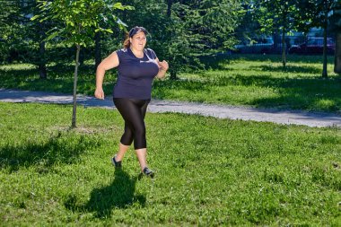 Woman with obesity jogging in public park on a sunny summer day. clipart