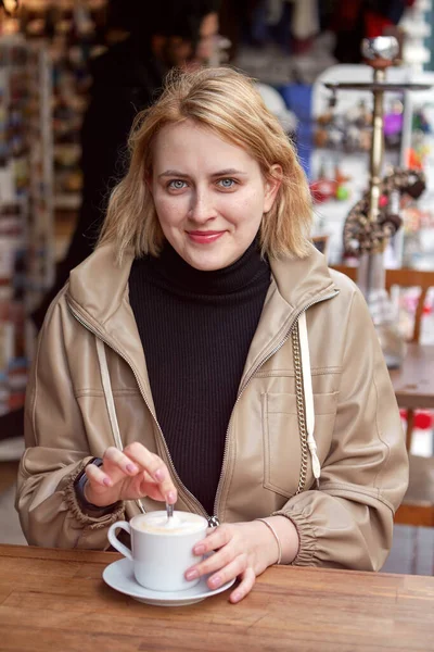 Kawa w ulicznej kawiarni dla młodej uśmiechniętej białej kobiety. — Zdjęcie stockowe