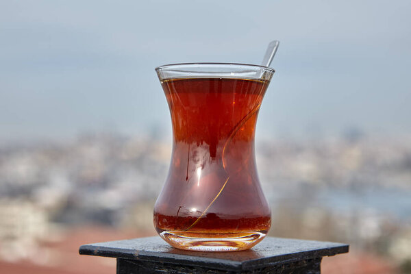 Armudu with Turkish tea stands on op rooftop fence, with defocused view of Istanbul.