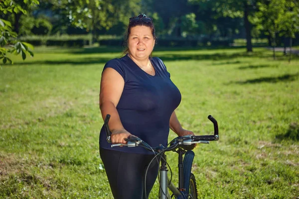 Stout mogen kvinna på cykeltur i offentlig park på solig sommardag. — Stockfoto
