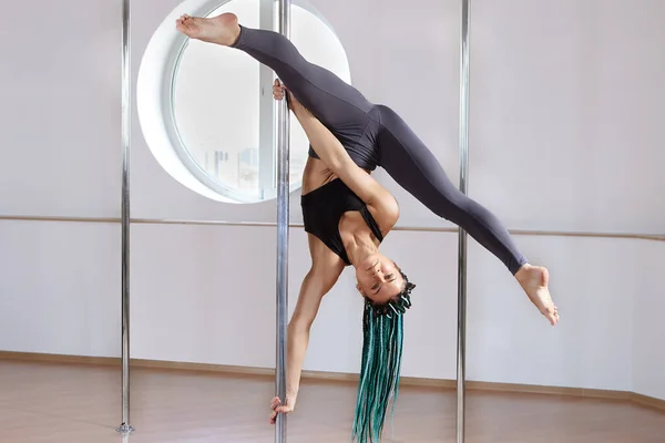 Woman demonstrates tricks on pole in gym of fitness studio. — Stockfoto