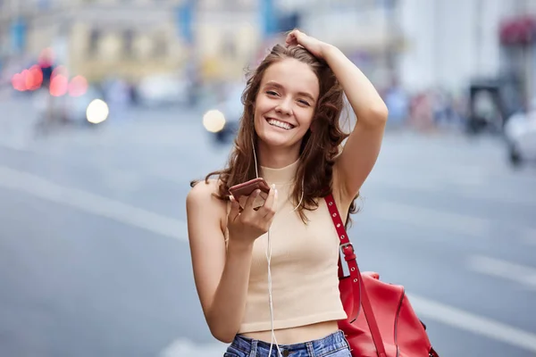 Młoda kobieta śmieje się podczas rozmowy telefonicznej na ulicy miejskiej. — Zdjęcie stockowe