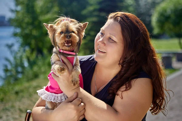 Stor byggkvinna med Yorkshire Terrier hund på armarna. — Stockfoto