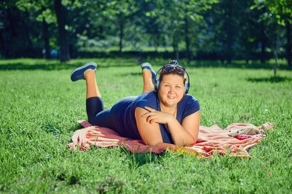 Kvinnan lyssnar på musik när hon vilar i en offentlig park på sommaren. — Stockfoto