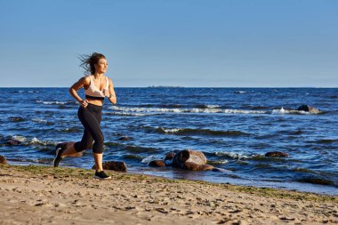 Beyaz kadın 30 yaşında, gündüz kumsalda koşuyor..