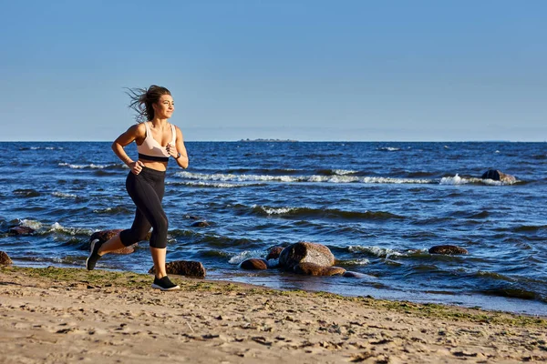 30歳の白人女性は昼間ビーチで走ります. — ストック写真