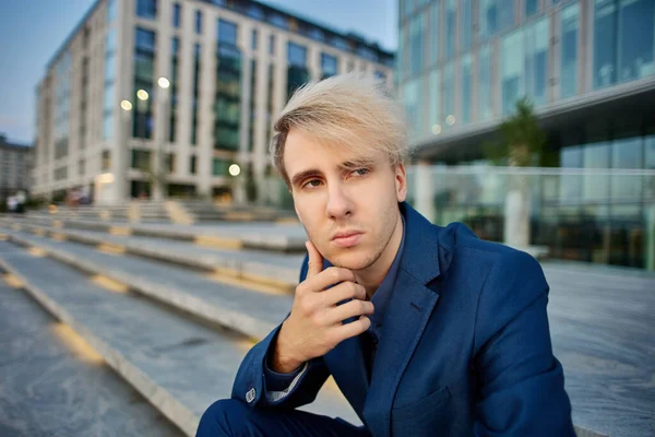 Serious blonde manager sits near business center on stairs. — Stock Photo, Image