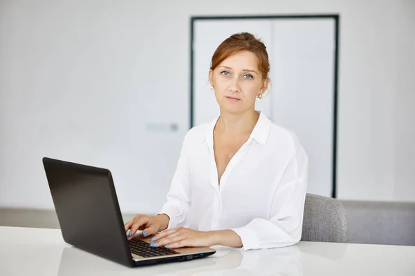 工作时穿着衬衫、拿着手提电脑的严肃女性. — 图库照片
