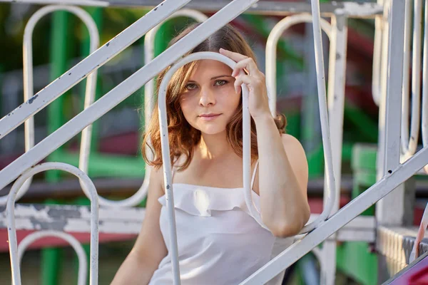 Atractiva mujer seria se sienta detrás de la cerca al aire libre. —  Fotos de Stock