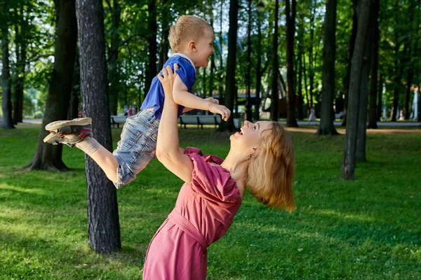 Happy woman holds little child in city garden. — Stock Photo, Image