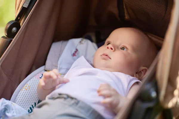 Menino de 4 meses encontra-se no carrinho enquanto caminha. — Fotografia de Stock