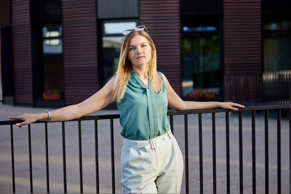 Slanke vrouw staat in de buurt van hek op zomerdag. — Stockfoto