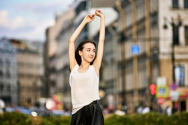 Une jeune femme souriante se promène dans le centre-ville le jour. — Photo