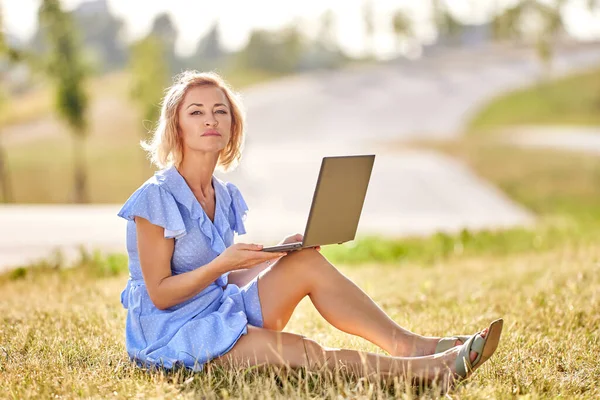 Smukła kobieta z laptopem siedzi w parku podczas spaceru. — Zdjęcie stockowe