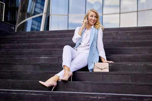 Gelukkige vrouw in zakenpak praat via mobiele telefoon op de trap. — Stockfoto