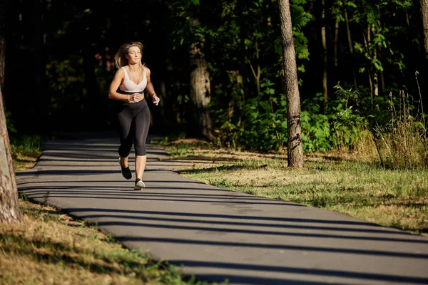 Mulher ativa corre no parque público no dia de verão. — Fotografia de Stock