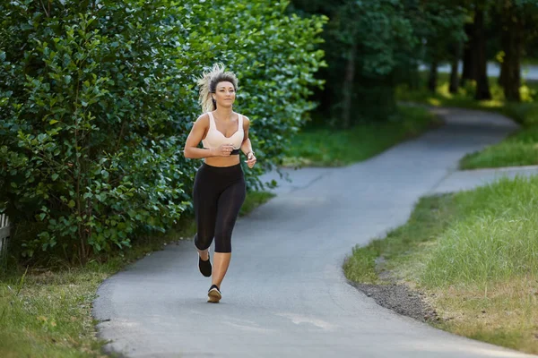 Aktiv kvinna i sportkläder körs i parken. — Stockfoto