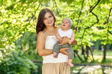 Anne çocuğu şehir bahçesinde elinde tutuyor..