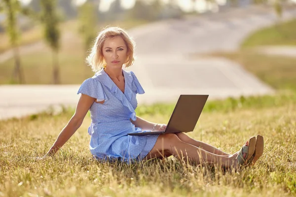 Frau mittleren Alters sitzt mit Laptop im Park. — Stockfoto