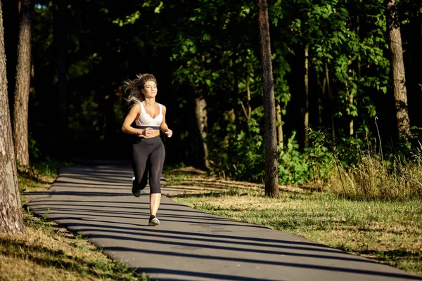 夏にはスポーツウェアを着た女性が森の中を走る. — ストック写真