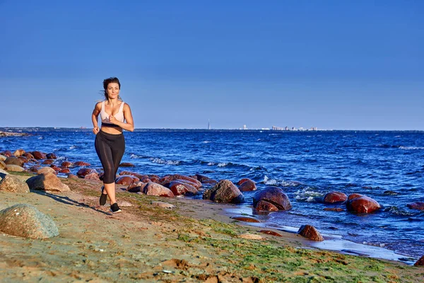 Active woman in sportswear runs near shore. — Stock Photo, Image