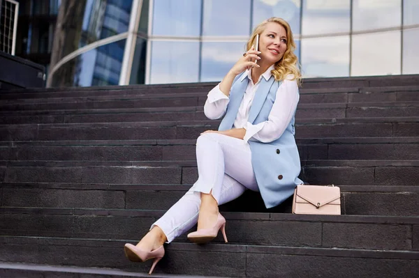 Smiling financial advisor talks by phone near office building. — Stock Photo, Image