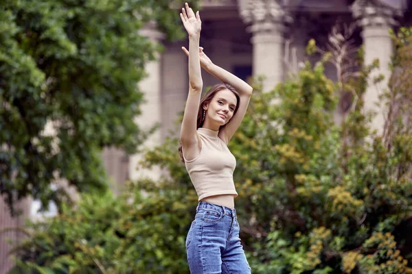Cheerful young woman in jeans walks in park. — Stock Photo, Image