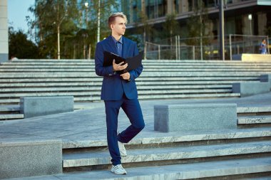 Belgeler için klasörü olan iş adamı büro merkezinin yanında duruyor.