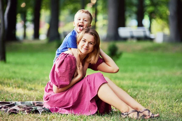 Cheerful woman and boy sit in park in summer. — Stock Photo, Image