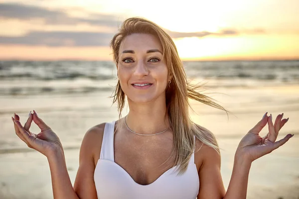 Mujer está haciendo yoga entrenamiento en la playa en la noche. — Foto de Stock