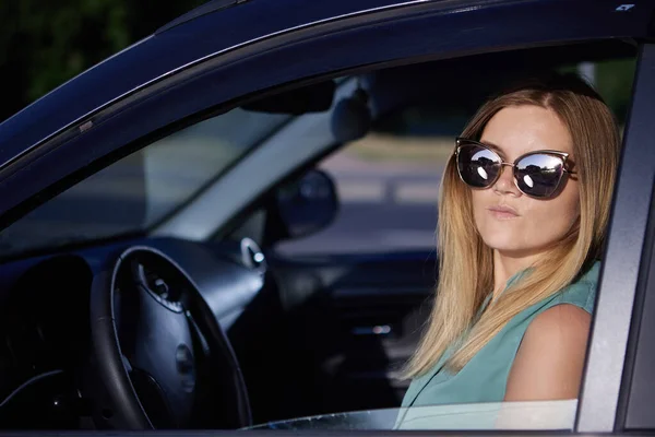 Motorista feminina em óculos de sol senta-se no carro. — Fotografia de Stock