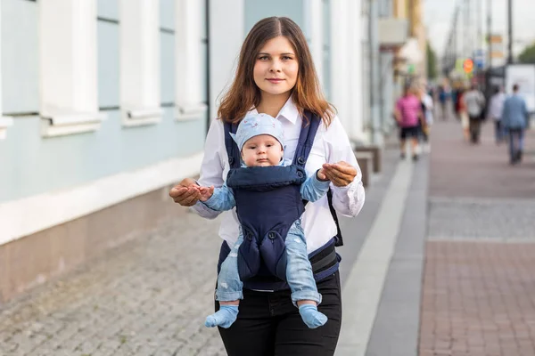 Mère avec petit enfant en fronde marche dans la rue. — Photo