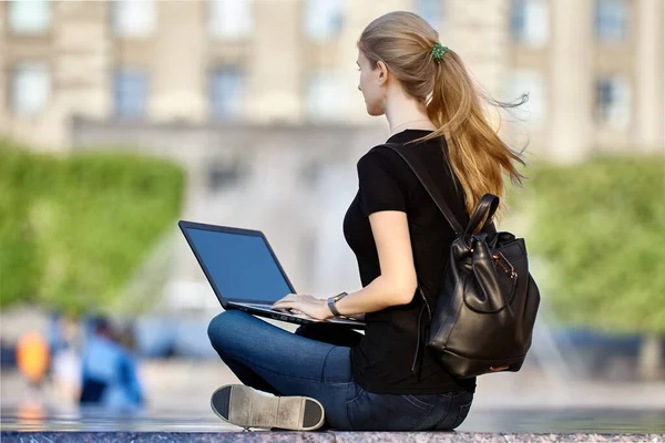 Frau mit Laptop sitzt an Sommertagen im Stadtgarten. — Stockfoto