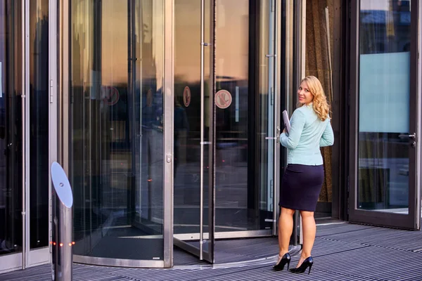 Sekretarz w garniturze biznesowym stoi przy drzwiach obrotowych. — Zdjęcie stockowe