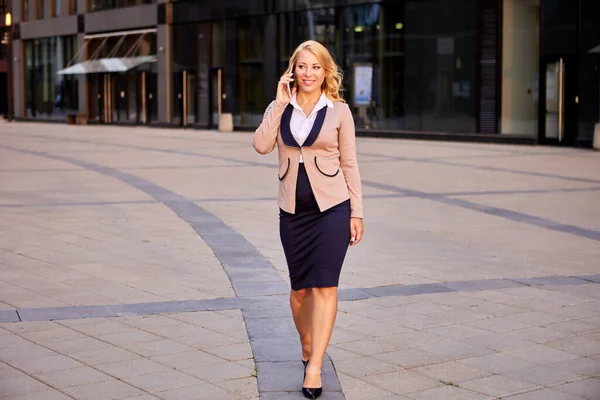 Gelukkig zakenvrouw praat met smartphone in de buurt van business center. — Stockfoto