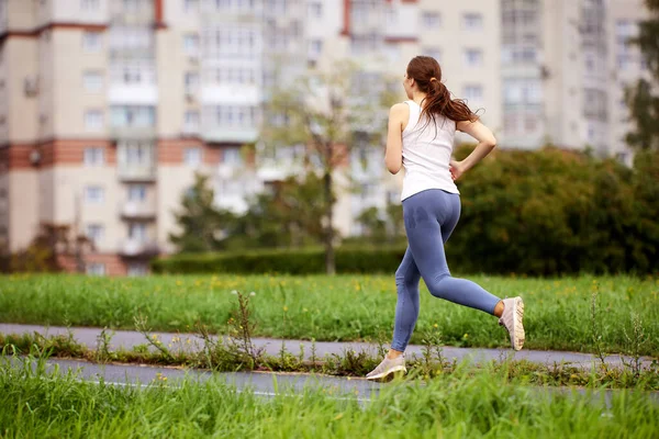 Back view of woman who runs in park at daytime. — Stock Photo, Image