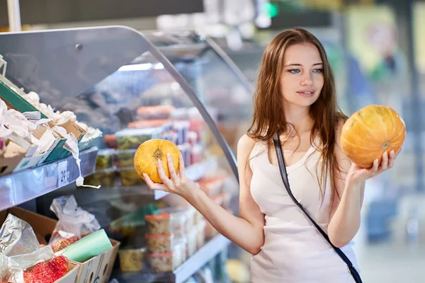 Mujer sostiene calabazas en tienda de comestibles durante las compras. —  Fotos de Stock